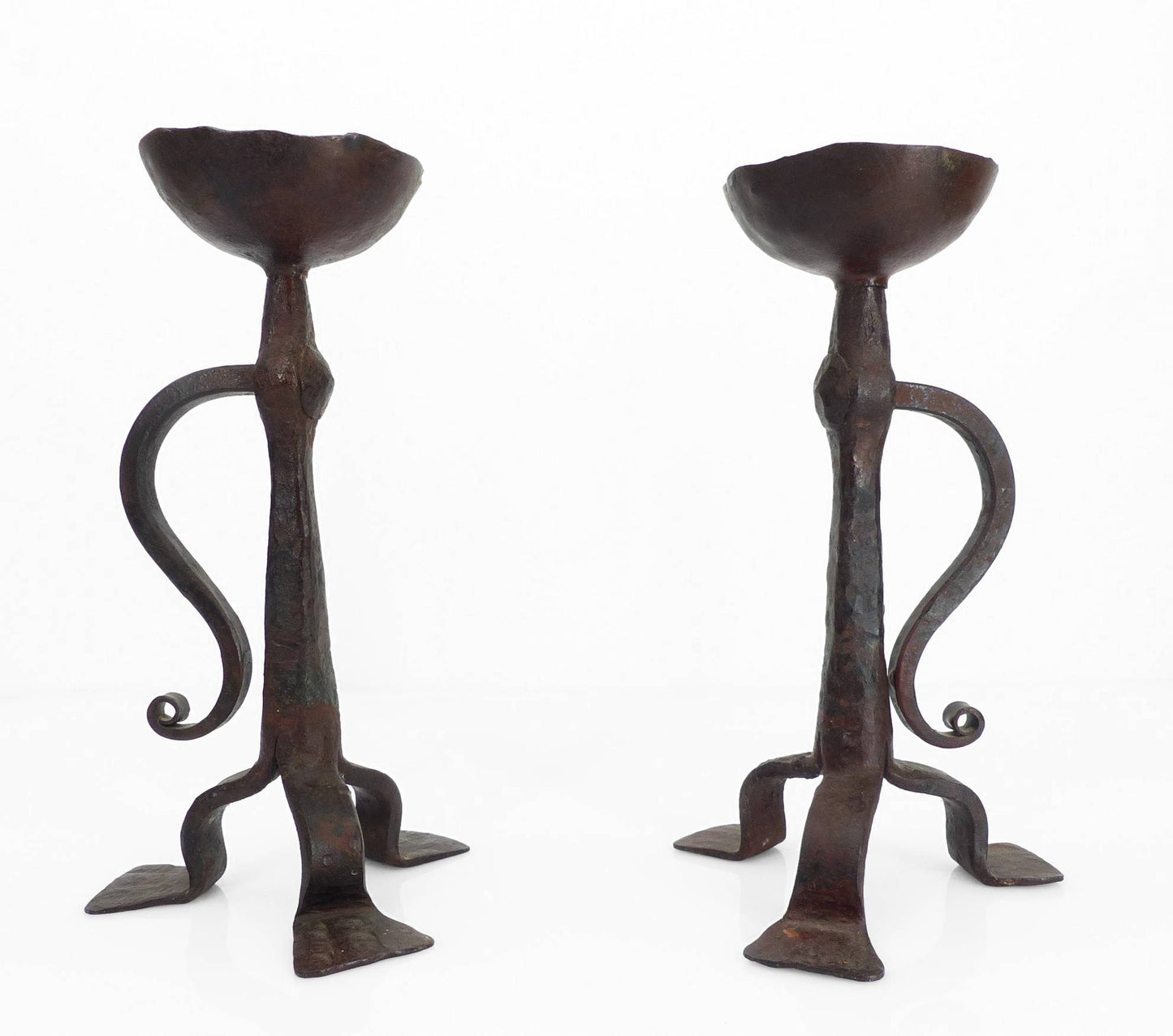 Paire de bougeoirs tripodes en fer forgé de style néogothique, travail artisanal français du début du XXe siècle avec coupelle à pique et volute forgée.