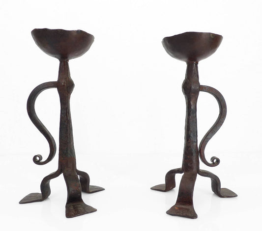 Paire de bougeoirs tripodes en fer forgé de style néogothique, travail artisanal français du début du XXe siècle avec coupelle à pique et volute forgée.